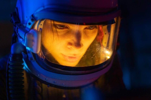 woman astronaut face bathed in orange light